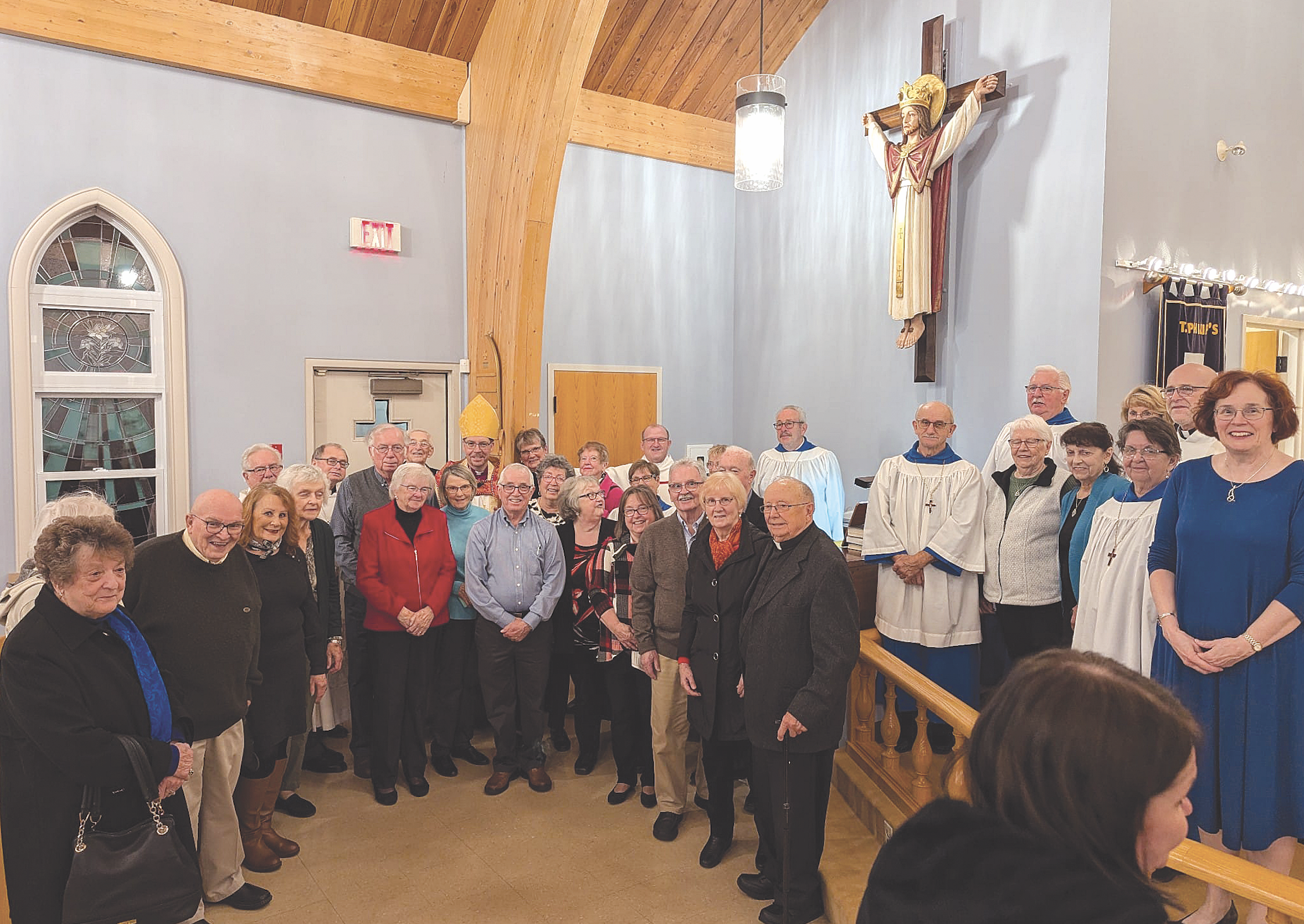 a group of people stand below a statue of Jesus on a wall in a church